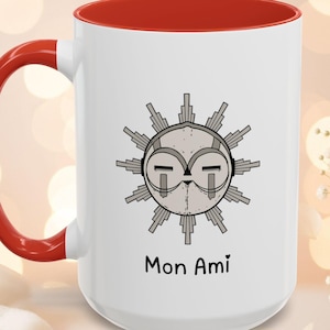 Peut inclure: Mug en céramique blanche avec intérieur et anse rouges. Le mug présente un motif de soleil stylisé en gris et noir, avec les mots "Mon Ami" imprimés en dessous. Idéal pour les boissons chaudes ou froides.