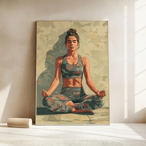 May include: A framed print of a person meditating in a yoga pose. The person is wearing a camouflage sports bra and leggings in shades of gray, orange, and green. The background is a neutral color, and the person is sitting on a wooden floor.