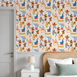 May include: Wallpaper featuring a repeating pattern of circus animals and performers in a whimsical design. The pattern includes elephants, zebras, lions, monkeys, and acrobats in bright colors like blue, pink, and yellow. The background is a cream color.
