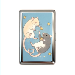 K&ouml;nnte beinhalten: Ein rechteckiges Metallgeh&auml;use mit poliertem Silberrahmen und einer hellblauen Illustration einer cremefarbenen Maus und einer grauen Maus, die zwischen gelben Sternen schweben. Die cremefarbene Maus greift nach einem Stern, w&auml;hrend die graue einen h&auml;lt.