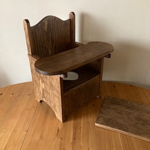 May include: A wooden high chair with a tray and a shelf underneath. The chair is stained a dark brown color and has a curved back.