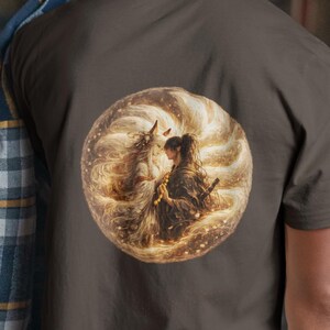 Può includere: Una t-shirt a maniche corte marrone scuro con una grafica circolare sul retro. La stampa raffigura una figura dai lunghi capelli fluenti che interagisce con una creatura mitica tra vortici di luce dorata e scintille. Una camicia a quadri blu, grigia e gialla è appoggiata su una spalla.