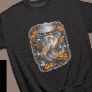 Könnte beinhalten: Ein schwarzes Langarm-Sweatshirt mit einem zentralen Grafikdruck eines weißen Kranichs vor einem Torii-Tor, umgeben von leuchtend orangefarbenen Kürbissen und kleinen blauen Lichtkugeln. Das Wort BLACK ist in weißer Schrift auf der linken Seite zu sehen.