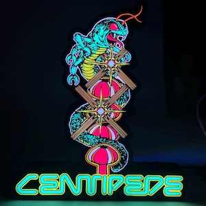 May include: A neon sign featuring a stylized snake with a teal body, red eyes, and an open mouth. The snake is wrapped around a series of pink and yellow shapes. The word "CENTIPEDE" is written in bright teal letters at the bottom.