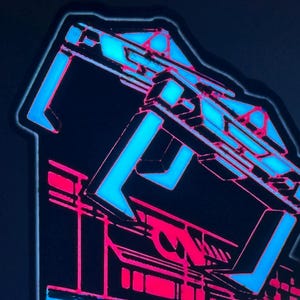 May include: A rectangular sticker featuring a stylised graphic design with a bold, bright blue geometric structure at the top and a vibrant pink architectural base. The design uses sharp lines and high-contrast colours against a dark background.