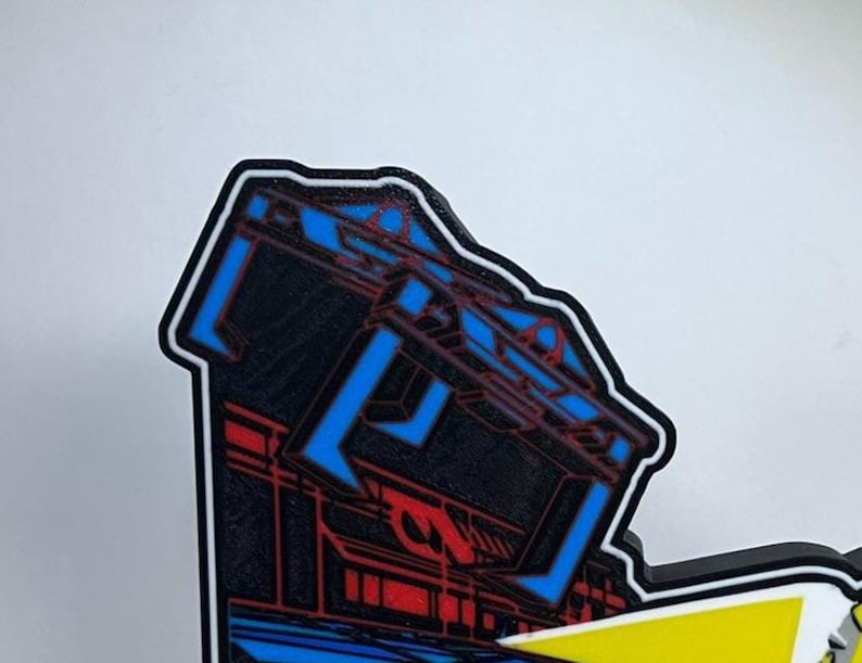 May include: A die-cut sticker featuring a stylised graphic of a dark structure with vibrant blue and red geometric line art. The design has a thick black border and a white outline, showcasing a sharp, angular aesthetic with high-contrast colours.