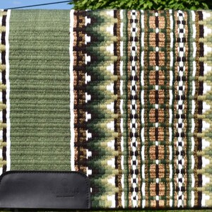 May include: A green and brown saddle pad with a geometric pattern. The pad features a central design of alternating brown, white, and green shapes, bordered by a solid green edge. A black leather piece is attached to the bottom.