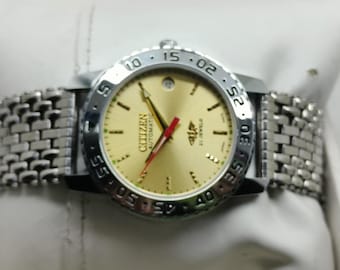 May include: A Citizen Automatic wristwatch with a gold-colored face, silver bezel, and a silver link band. The watch face displays the Citizen logo, the words "AUTOMATIC" and "21 JEWELS". The watch hands are gold and red.
