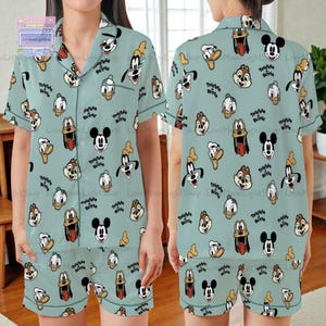 A woman wearing a light blue pajama top with a repeating pattern of cartoon character faces, including Mickey Mouse, Goofy, Donald Duck, and others.