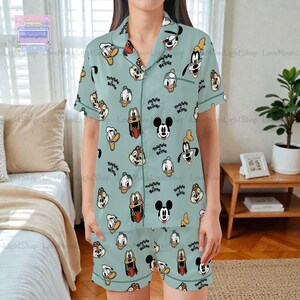 A person wearing a pajama top with a pattern of cartoon faces, including Mickey Mouse, Donald Duck, Goofy, and other popular Disney characters.