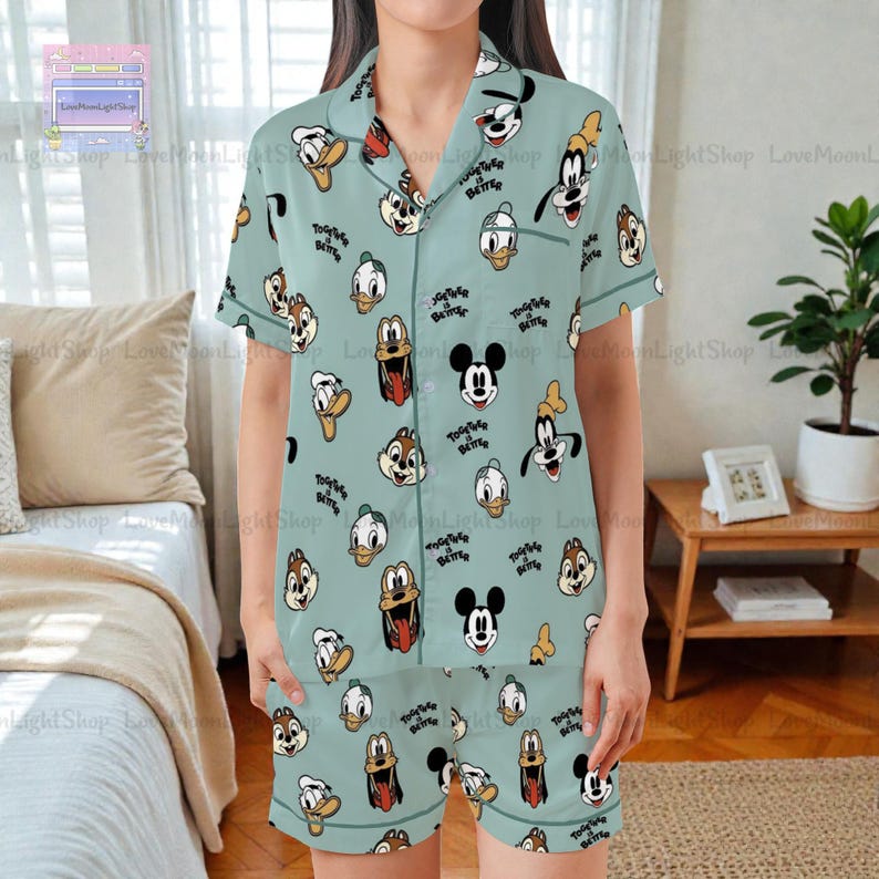 A person wearing a pajama top with a pattern of cartoon faces, including Mickey Mouse, Donald Duck, Goofy, and other popular Disney characters.