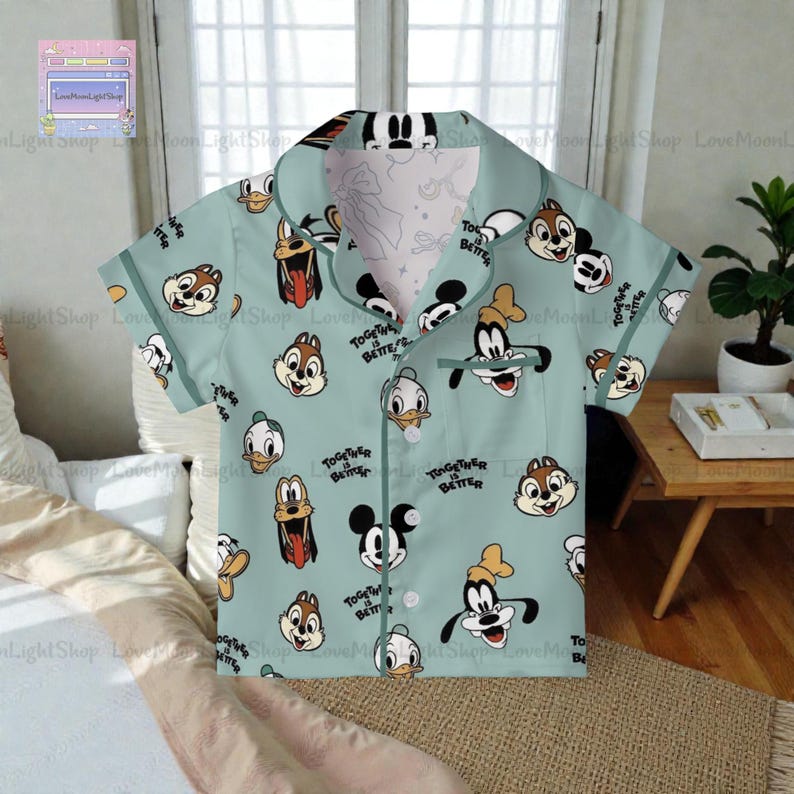 A light blue printed shirt with various cartoon character faces, including Goofy, Donald Duck, and other popular Disney characters, printed on it.