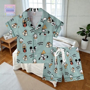 A pajama set featuring various Disney characters, including Goofy, Mickey Mouse, Donald Duck, and Donald Duck, printed on a light blue fabric.