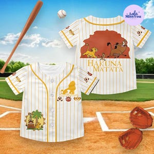 May include: White baseball jersey with yellow pinstripes and a cartoon graphic. The jersey features the text "Hakuna Matata" and a lion silhouette. A baseball bat, ball, and mitts are also in the image.