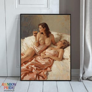 May include: A framed art print featuring two figures in a bedroom setting. One figure is holding a glass of amber liquid, while the other reclines on a bed. Both figures are wearing light pink lingerie. The artwork has a vintage aesthetic.