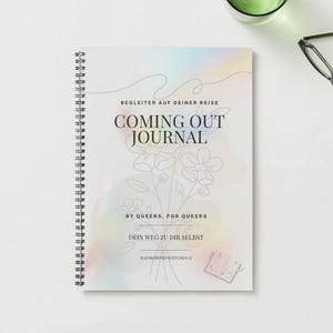 以下が含まれることがあります： 「COMING OUT JOURNAL」のタイトルが表紙に書かれたスパイラル綴じのジャーナル。花柄のイラストと「BY QUEERS, FOR QUEERS」の文字が特徴です。ジャーナルは白い表面に置かれ、メガネと液体が入ったグラスが近くにあります。