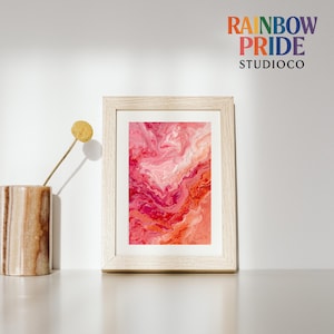 Könnte beinhalten: Gerahmter Kunstdruck mit abstraktem Muster in Rosa- und Rottönen. Das Kunstwerk wird in einem hellen Holzrahmen präsentiert. Das Logo von Rainbow Pride Studio Co. ist oben rechts sichtbar.