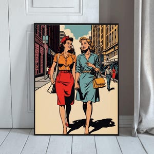 Op de afbeelding: Een ingelijste kunstdruk met een illustratie in stripstijl van twee personen die door een stadsstraat lopen. De een draagt een gele blouse met stippen en een rode rok, de ander een lichtblauwe jurk en een beige handtas.