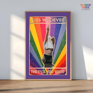 Può includere: Stampa artistica incorniciata con bordo viola e cornice interna dorata. L'opera presenta una figura con una camicia bianca che viene tirata sopra la testa, con uno sfondo arcobaleno. Il testo recita "KISS WHOEVER THE F*CK YOU WANT."