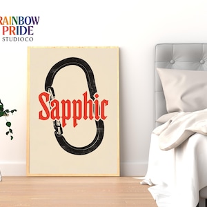 Könnte beinhalten: Ein gerahmter Kunstdruck mit cremefarbenem Hintergrund. Der Druck zeigt einen schwarzen Karabinerhaken mit dem Wort "Sapphic" in roter gotischer Schrift. Das Logo Rainbow Pride StudioCo befindet sich in der oberen linken Ecke.