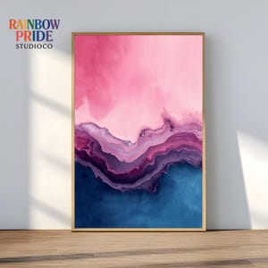 Può includere: Stampa artistica astratta in una cornice dorata. L'opera presenta un gradiente di colori, tra cui rosa, viola e blu. La parte superiore è rosa, che sfuma in viola e poi in blu nella parte inferiore. Il testo "RAINBOW PRIDE STUDIOCO" è nell'angolo in alto a sinistra.