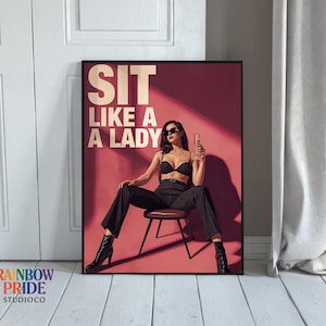 Könnte beinhalten: Gerahmtes Poster mit dem Text "SIT LIKE A LADY" in Weiß. Das Bild zeigt eine Frau in schwarzer Kleidung, die auf einem Hocker sitzt und ein Sektglas hält. Der Hintergrund ist rot.