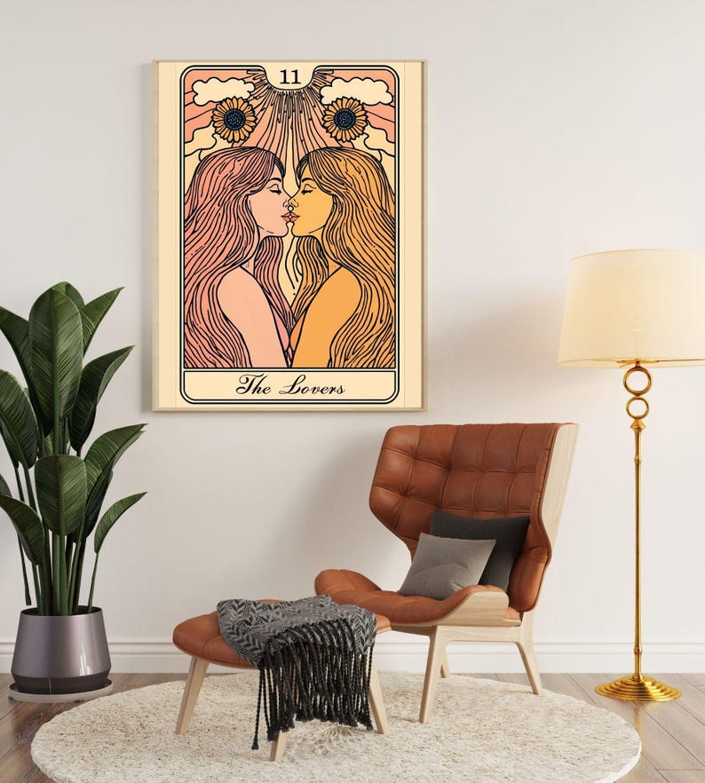 May include: A framed tarot card art print featuring two women kissing, with long flowing hair and a sunflower design. The card is labeled "The Lovers" and has the number 11 at the top. The artwork is displayed in a living room setting.