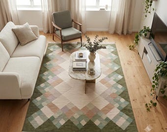 Puede incluir: Una alfombra rectangular con un patrón geométrico de diamantes en tonos verde oliva, rosa suave y crema. La alfombra tiene una textura tejida con flecos en los lados cortos, situada bajo una mesa de centro ovalada de mármol en una sala.