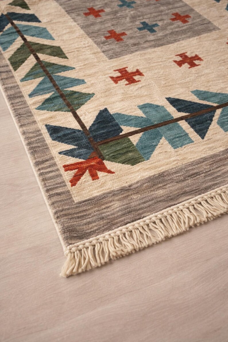 Puede incluir: Alfombra beige y gris con un patr&oacute;n geom&eacute;trico. La alfombra presenta un borde con formas azules, verdes y rojas, y un dise&ntilde;o central con cruces rojas y azules. La alfombra tiene una franja en el borde.