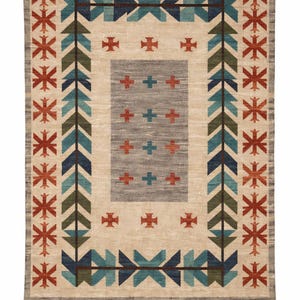 Puede incluir: Alfombra rectangular con un campo central beige y un borde gris. Presenta patrones geom&eacute;tricos en turquesa, verde, azul marino y rojo. El dise&ntilde;o incluye flechas, cruces y motivos de estrellas, creando una est&eacute;tica del suroeste o tribal.