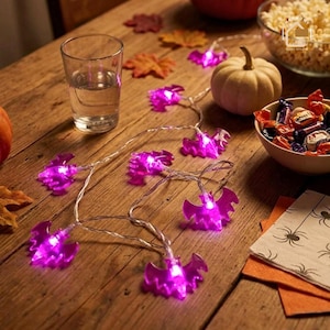 May include: A string of purple LED lights shaped like bats. The decorative light strand features multiple translucent purple bat figures that glow when illuminated, connected by a thin, clear wire, creating a festive accent for seasonal decor.