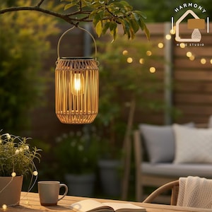 Pode incluir: Uma lanterna suspensa para exterior com um design de bambu tecido. A lanterna emite um brilho quente da lâmpada no interior. A lanterna está suspensa de um galho de árvore, criando um ambiente acolhedor. O fundo inclui uma cerca de madeira e luzes de corda.
