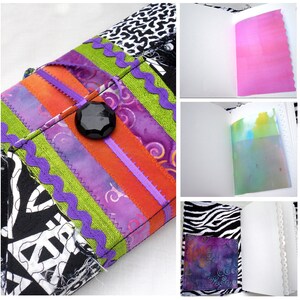 May include: A handmade journal with a colorful fabric cover. The cover features a black button and a variety of patterned fabrics, including zebra print, floral, and stripes. The journal is open to reveal blank pages.