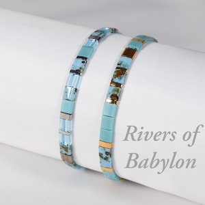 Peut inclure: Deux bracelets de perles turquoise et dorées. L'un présente des perles rectangulaires, l'autre un mélange de perles rectangulaires et cylindriques. Le texte "Rivers of Babylon" est visible.