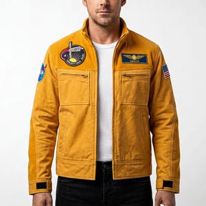 May include: Mustard yellow jacket with multiple patches, including one with the text "PROJECT MOSQUITO". The jacket has a ribbed collar and shoulder panels, two front pockets, and a small American flag patch. The jacket has the name "GRACE" on a patch.