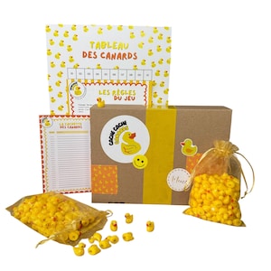 May include: A boxed game set with yellow rubber duckies. The set includes a game board, rule sheet, and small bags filled with miniature duck figurines. The box has the text "TABLEAU DES CANARDS" and "LES REGLES DU JEU".