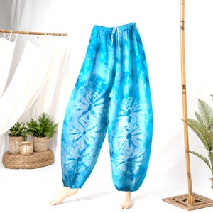 May include: Blue tie-dye harem pants with a drawstring waist. The pants feature a light blue and white spiral pattern on the legs. The loose-fitting pants are made of a lightweight fabric.