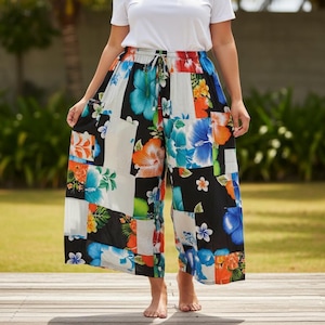 May include: Colorful patchwork palazzo pants featuring a vibrant floral print in shades of blue, orange, and white against a black background. The pants have a drawstring waist and wide legs, perfect for a casual, breezy look.