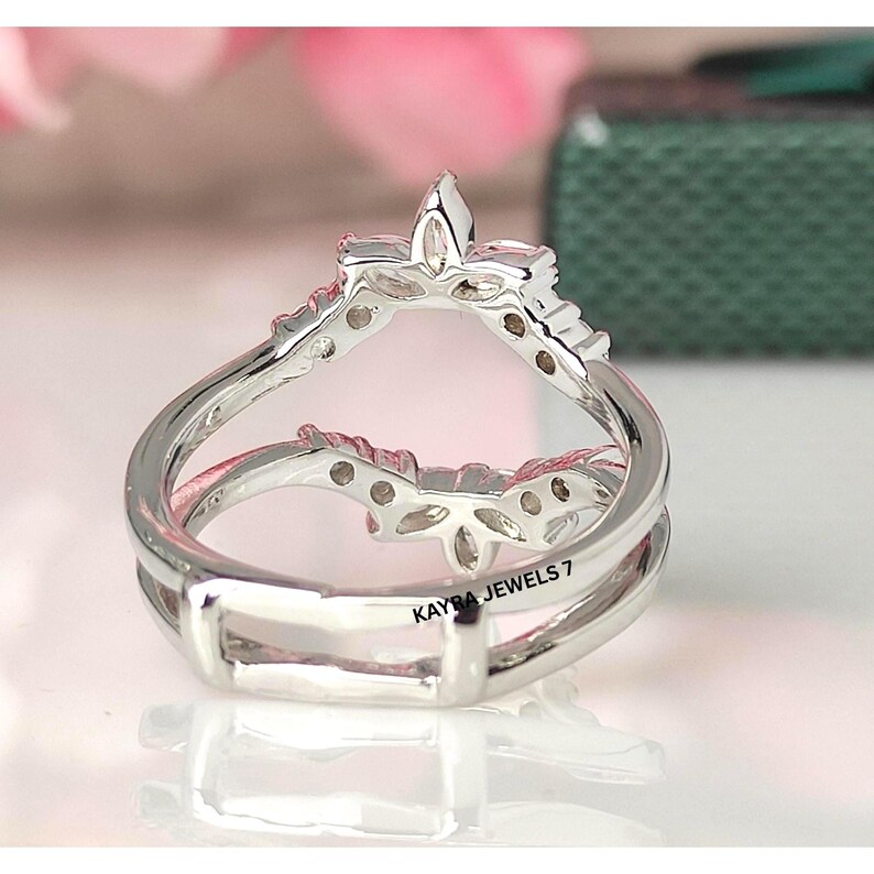 Puede incluir: Un anillo de plata con un dise&ntilde;o &uacute;nico. El anillo presenta una parte superior en forma de corona con un elemento central puntiagudo y peque&ntilde;os detalles decorativos. La banda tiene un dise&ntilde;o de doble capa. El texto "KAYRA JEWELS 7" es visible en el anillo.