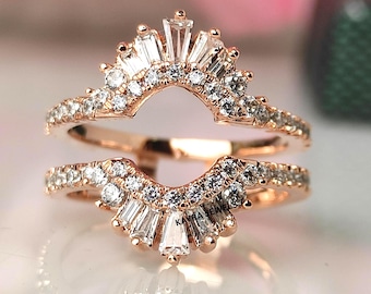 Puede incluir: Protector de anillo de oro rosa con un halo de diamantes baguette y redondos. El anillo presenta un diseño curvo con una fila de pequeños diamantes a lo largo de la banda. La parte superior del anillo tiene un diseño de rayos de sol con diamantes baguette más grandes.