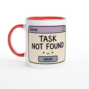 May include: A white ceramic mug with a bright red handle and interior rim. The front features a graphic of a computer error window with a light purple header, a beige body, and the black text "ERROR" and "TASK NOT FOUND" with an "OKAY" button.