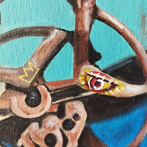 May include: Close-up of an abstract painting featuring a brown, circular structure with a turquoise background. A small, colorful, painted element with red and yellow accents is visible. The painting has a textured appearance.