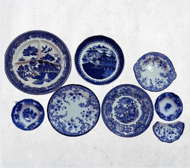 May include: A collection of blue and white porcelain plates and dishes. The plates feature various patterns, including floral designs and scenic landscapes. The arrangement includes plates of different sizes and shapes, showcasing a classic aesthetic.