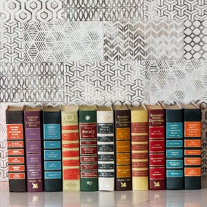May include: A collection of vintage Reader's Digest Condensed Books, each with a unique color scheme and title. The spines display titles like "Secret Missions" and "Home Mountain", with a decorative patterned background.