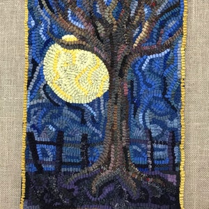 May include: A craft kit featuring a rug hooking pattern of a tree with a full moon in the background. The rug hooking pattern is made up of various shades of blue, yellow, and brown wool.