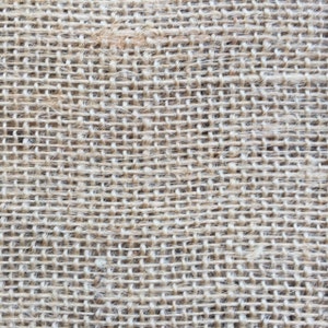 May include: Close-up of a natural brown burlap fabric with a woven texture. The fabric has a rough, coarse feel and is made from natural fibres.