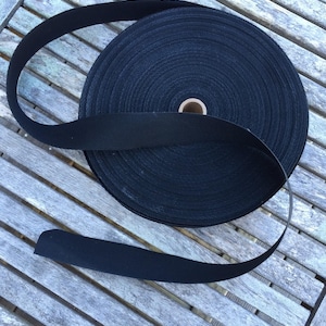 Puede incluir: Un rollo de cinta de algodón negra, un tipo de tejido fuerte y tejido que se utiliza a menudo para correas, cinturones y otras aplicaciones.