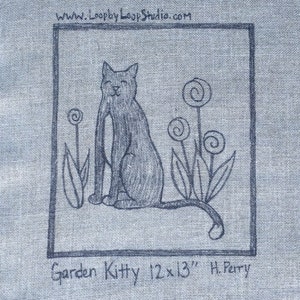 Puede incluir: Dibujo en blanco y negro de un gato sentado en un jardín con flores. El dibujo está sobre un fondo de tela azul. El texto "Garden Kitty 12x13" H. Perry está debajo del dibujo.