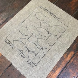 May include: A burlap fabric with a black outline of a school of fish. The text "School of Fish" and "11x14" H. Perry" is printed on the fabric.