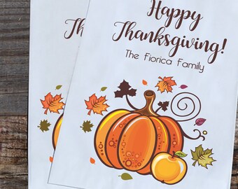 May include: Two white paper bags with a Thanksgiving theme. The bags feature a pumpkin, leaves, and the text "Happy Thanksgiving! The Fiorica Family."